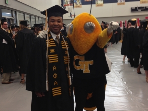 Hope graduated in 2014 with a degree in psychology. Man in graduation regalia stands with Georgia Tech mascot Buzz.