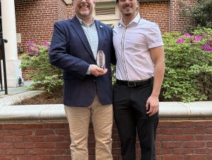 Mark Sprouse and Arya Akbarshahi A man and a male college student shake hands and hold up an award.