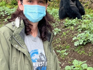 A woman wearing a mask stands near a gorilla.